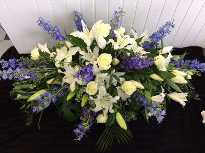 Casket Spray - Blue & White - A caskey spray filled with white Roses, Lillies & electric blue Delphinium with a mixture of seasonal foliages