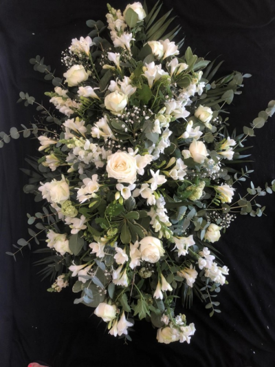 All White Casket Spray - A beautiful all white casket spray bursting with seasonal flowers & foliages including Roses.