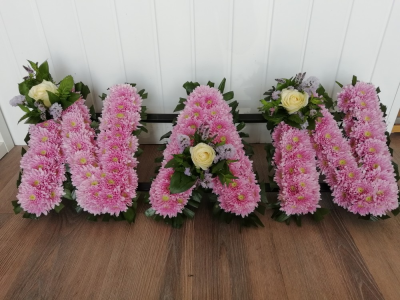 NAN - Pink & White - A NAN floral tribute with foliage edge, pale pink based chrysanthemums and finished with a white Rose & foliage cluster