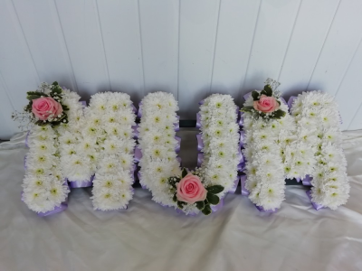 MUM - Lilac & Pale Pink - A MUM floral tribute with lilac ribbon edge, white based chrysanthemums and finished with a pale pink Rose, Gypsophila & foliage cluster