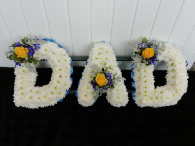 DAD - Blue & Yellow - A DAD floral tribute with blue ribbon edge, white based chrysanthemums and finished with a yellow Rose, electric blue Delphinium & foliage cluster