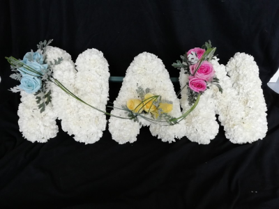 NAN - Carnations - A NAN floral tribute based in white Carnations and finished with a Rose & foliage cluster.