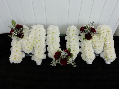 MUM - Red & White - A MUM tribute in letters massed in white double chrysanthemums with a Red carnation, gypsophila & foliage cluster. Finished off with a white ribbon edge.