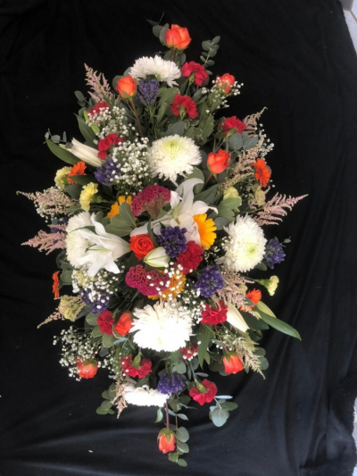 Colourful Casket Spray - A casket spray filled with an array of brightly coloured flowers with a mixture of seasonal foliages