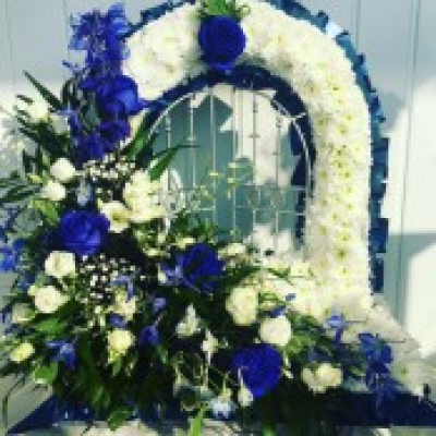 Gates Of Heaven - Blue & White - Gates of heaven tribute massed in white double chrysanthemums with a Blue & White cluster. Finished off with a blue ribbon edge