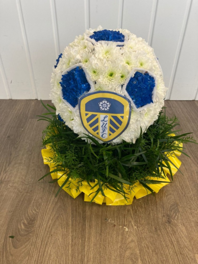 Leeds United Football - Football based in white crysanthenums with club badge & placed onto colour co-ordinating ribbon edged foliage with a rose cluster.